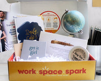 A Work Space Spark subscription box with a few small notebooks, a journal, and a ring toss game.